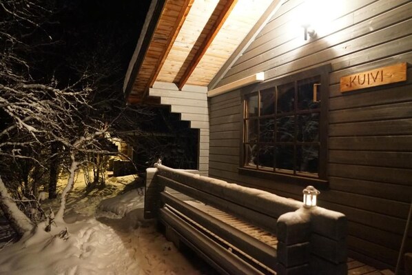 A wooden cabin with a bench outside, a window with a sign, and snow on the ground. - Muotkan Ruoktu Tunturikyla (Inari)
