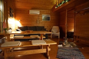 A cozy cabin interior with a wooden bench, a sofa, and a dog. - Muotkan Ruoktu Tunturikyla (Inari)
