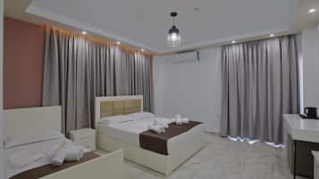 Una habitación de hotel con cama, mesitas de noche, escritorio y lámpara colgante.