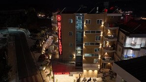 Un hotel de varios pisos con un letrero rojo llamativo, balcones y áreas de estar al aire libre.