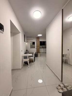 A modern interior with a dining area, a sofa, a mirror, and a kitchen in the background. - Comfortable Stay near Tirana City Center - Great Location (Tiranë)