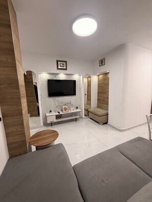 Un salon moderne avec un téléviseur à écran plat, une table basse ronde et un canapé.
