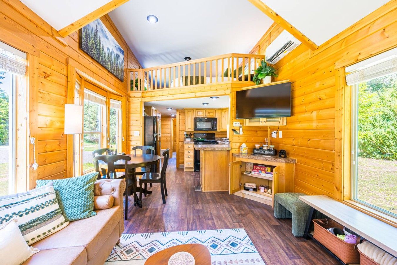 Interior acogedor de una cabaña con comedor, cocina y un dormitorio en la buhardilla.