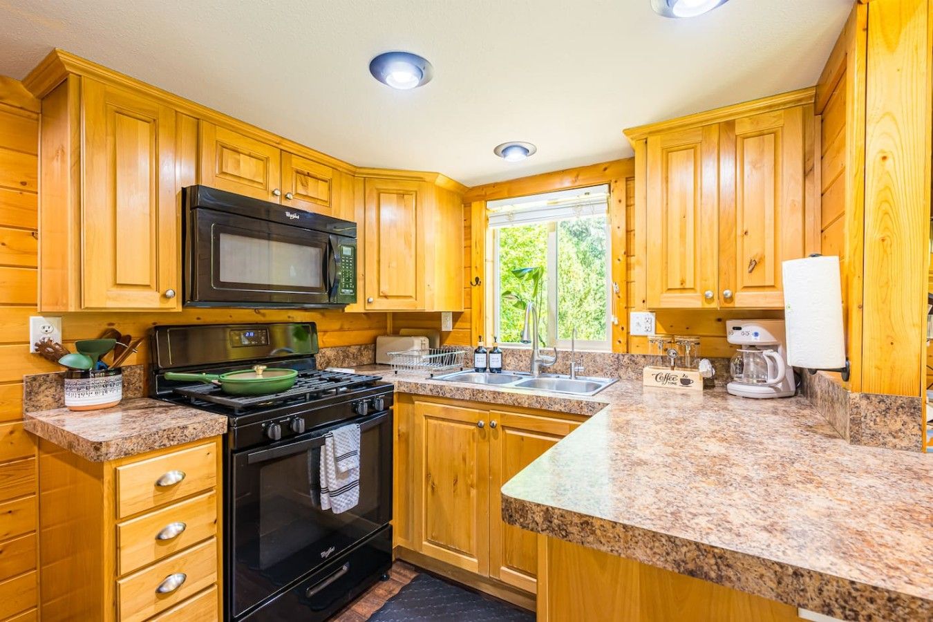 A kitchen with wooden cabinets, a black stove, a microwave, and granite countertops.