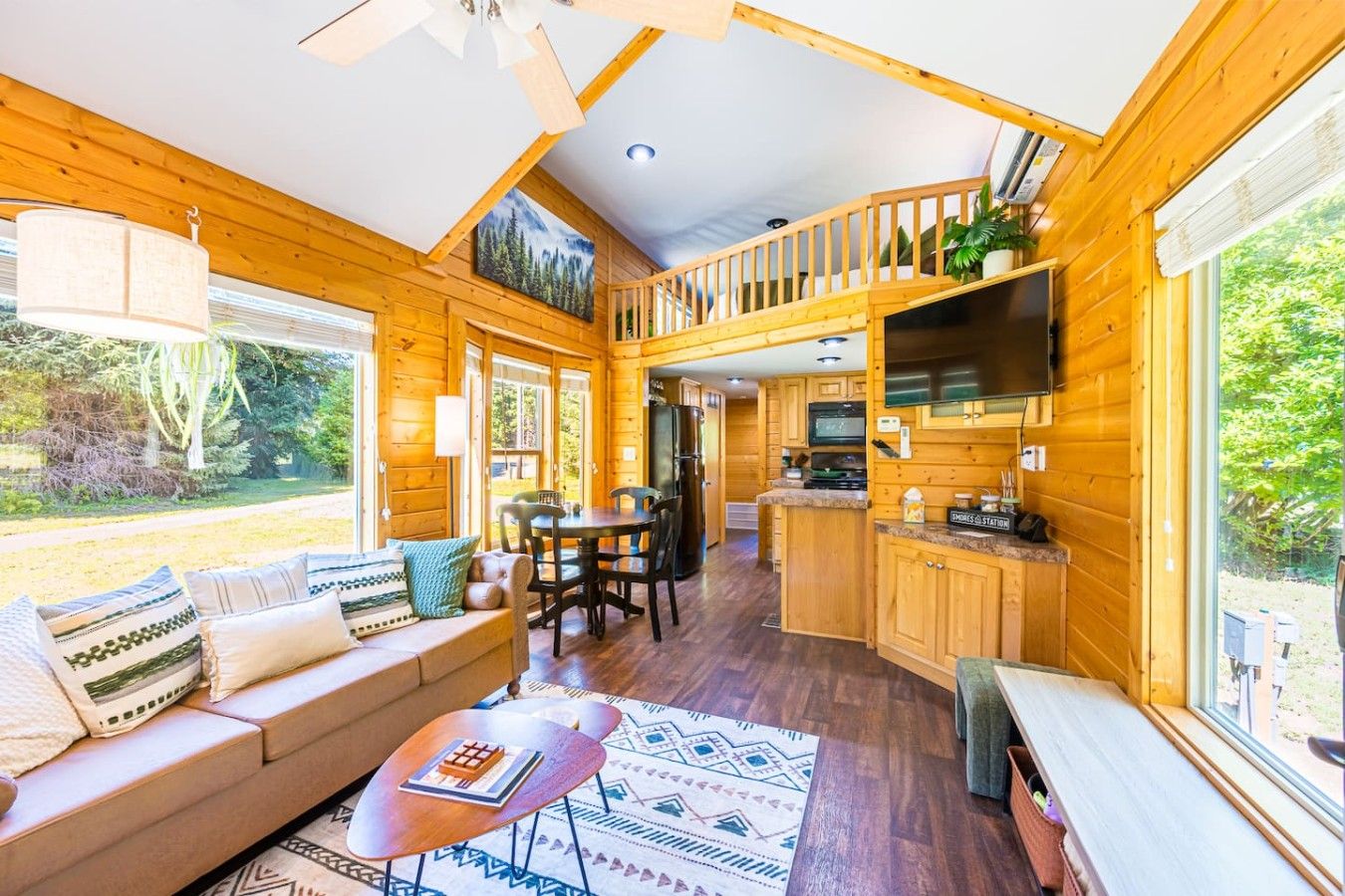 A cabin interior with a living area, dining space, kitchen, and a balcony.