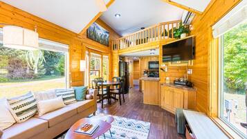 A cabin interior with a living area, dining space, kitchen, and a balcony.