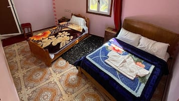 A bedroom with two beds, a window with curtains, a ceiling fan, and patterned floor tiles.