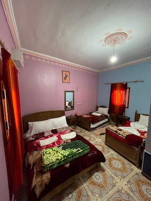 A bedroom with two beds, a ceiling fan, a mirror, and patterned floor tiles. - MAISON D'HOTES ANISSA HOTEL & RESTAURANT (Tinghir)
