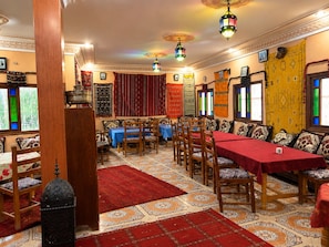 A traditional inn with wooden furniture, patterned carpets, and colorful hanging textiles. - MAISON D'HOTES ANISSA HOTEL & RESTAURANT (Tinghir)