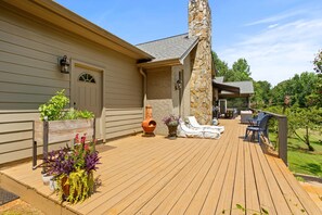 A wooden deck with outdoor furniture, a stone chimney, and a covered patio area. - Spiritual Retreat on 12-Acres in Travelers Rest - Sauna, Cold Plunge, Hottub (Travelers Rest)