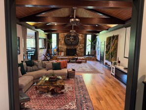 A spacious living room with a large sofa, a coffee table, and a fireplace. - Spiritual Retreat on 12-Acres in Travelers Rest - Sauna, Cold Plunge, Hottub (Travelers Rest)