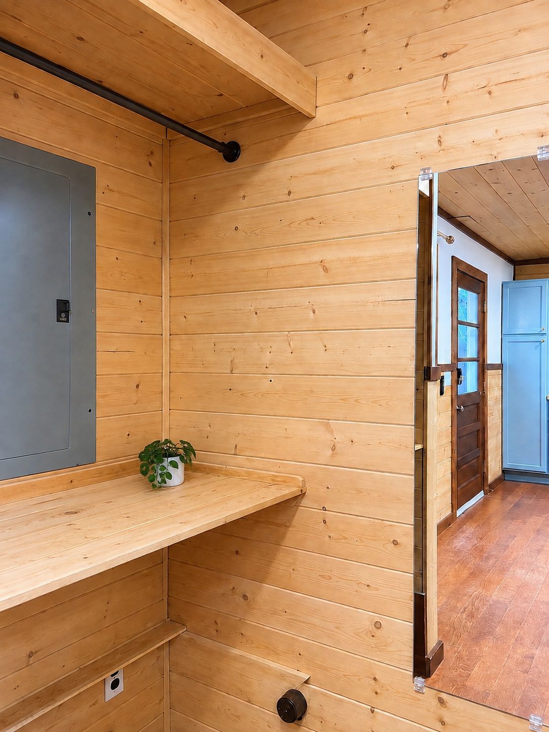 A wooden interior with a bench, a door, and a small plant.