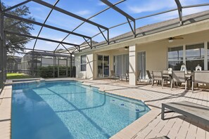 Piscina con cerramiento de vidrio, mobiliario exterior y zona de terraza.
