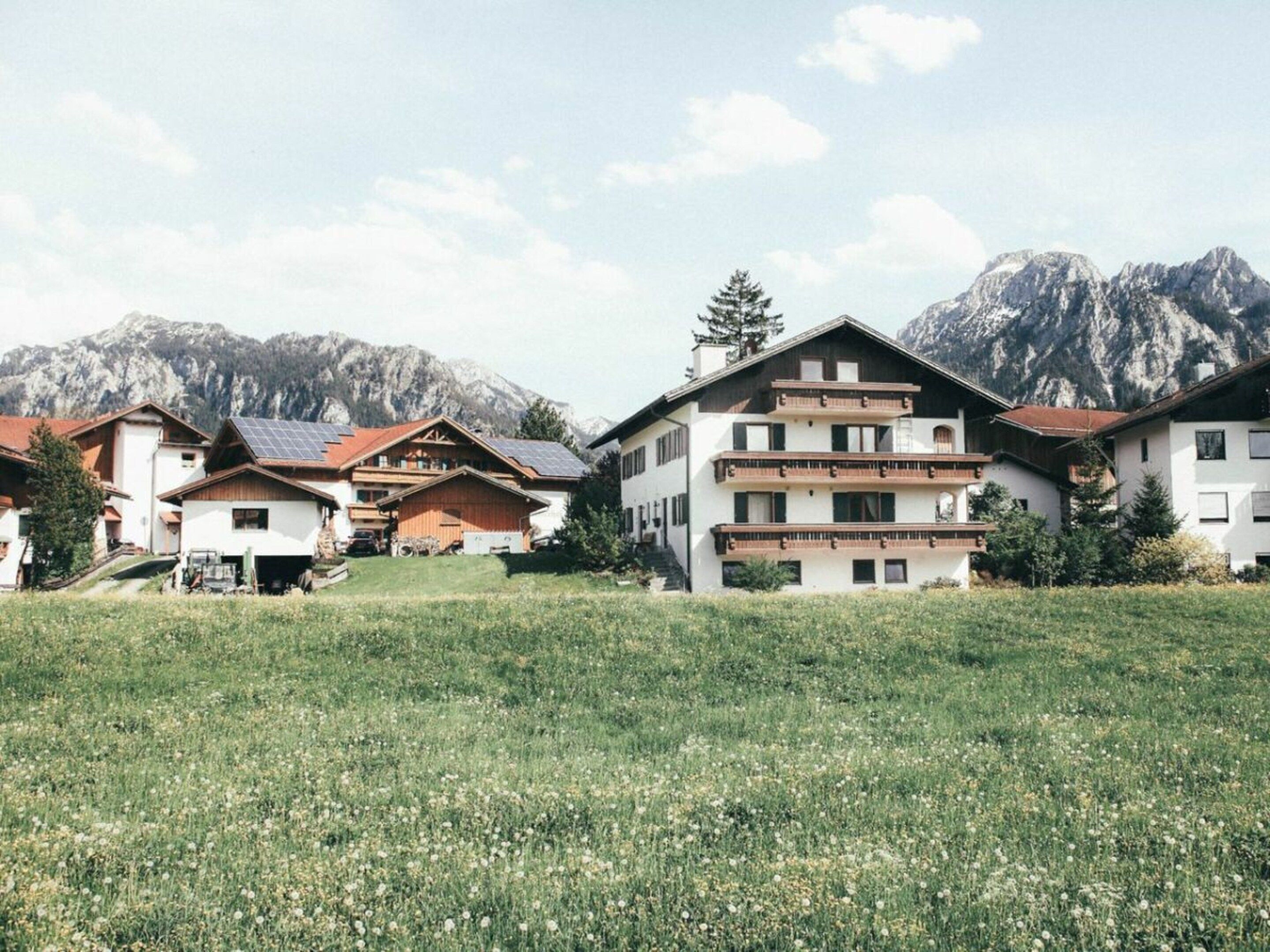 Eine Reihe traditioneller Chalets mit Balkonen vor einer Bergkulisse.