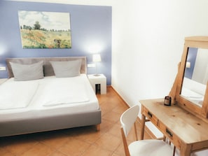 A bedroom with a bed, bedside tables, a desk with a mirror, and a painting on the wall. - House Luna - Apartment Luna 1 (Schwangau)