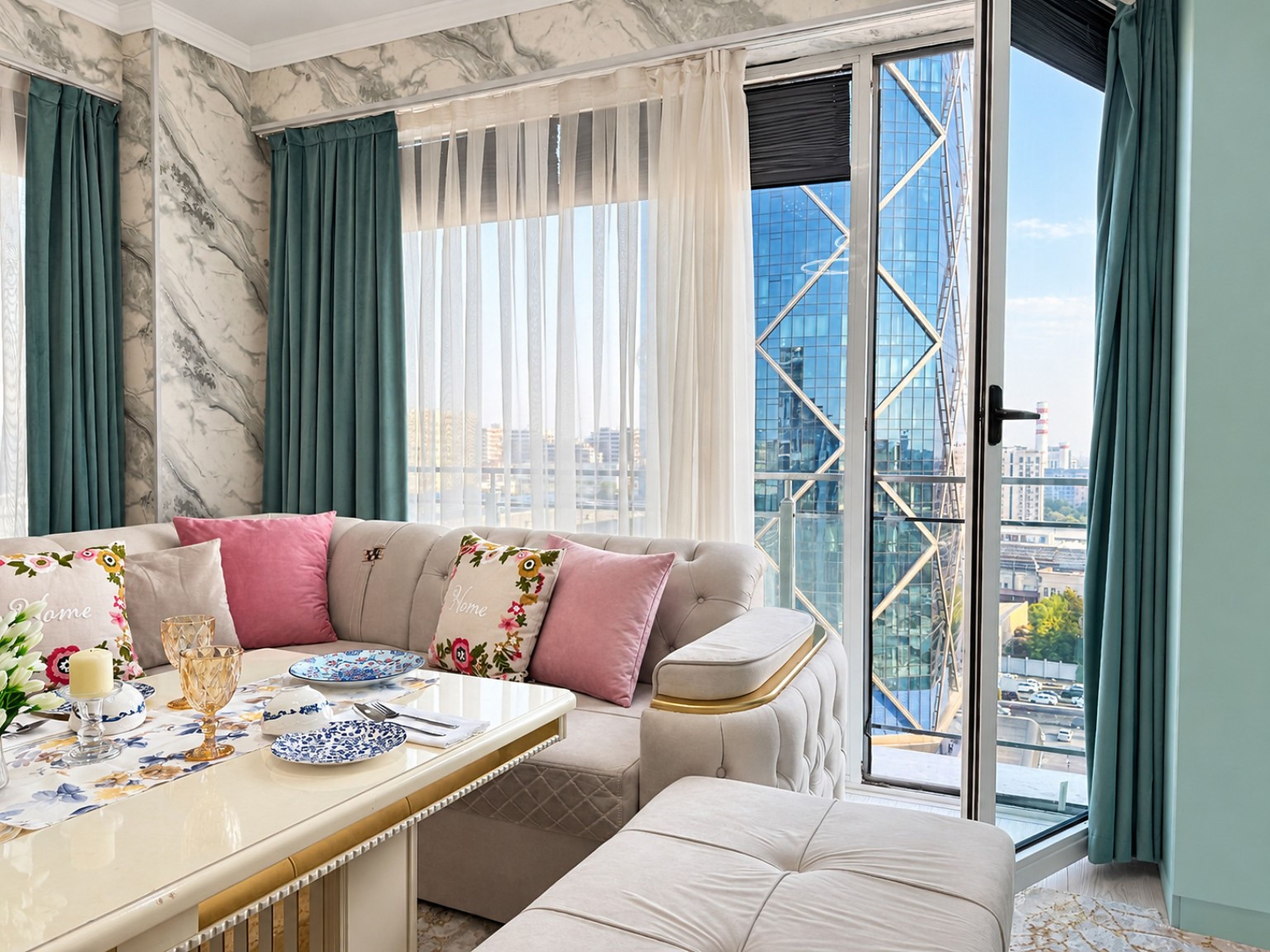 A modern living room with a sofa, a dining table set with plates and glasses, and a view of a cityscape through large windows.