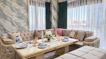 Un coin repas avec un mur en marbre, un canapé, une table dressée avec des assiettes, des verres et une bougie.