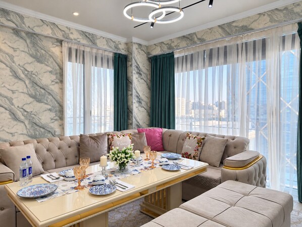 Un comedor moderno con pared de mármol, un sofá y una mesa lista para comer.