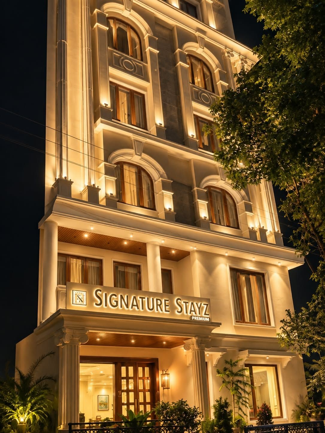 Um hotel com vários andares e uma placa na entrada que diz 'Signature Stayz Premium'.