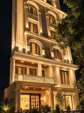 Un hotel de diverses plantes amb un rètol a l'entrada que diu 'Signature Stayz Premium'.