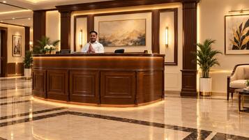 A reception desk with a receptionist, framed artwork on the wall, and a polished marble floor.