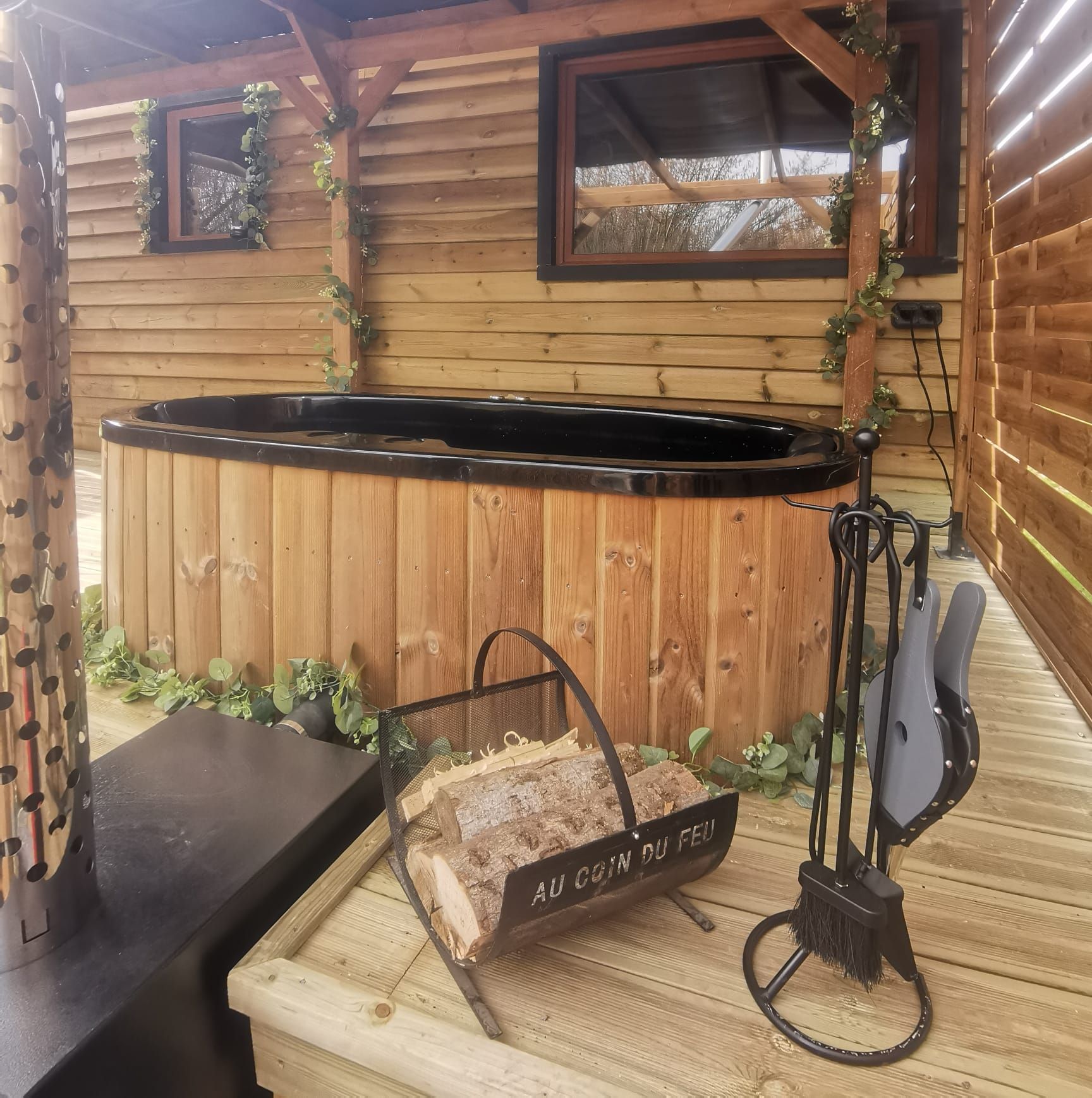 Eine rustikale Holzhütte mit Whirlpool, Kamin und einem Holztisch mit einem Schild, auf dem 'AU COIN DU FED' steht.