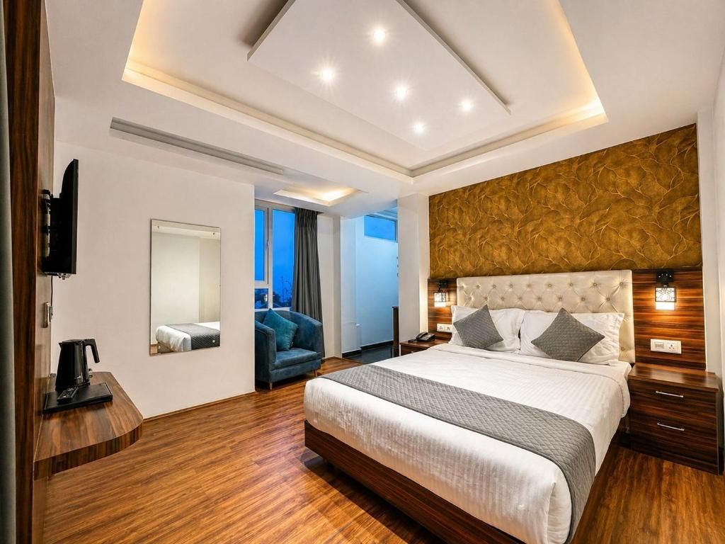 Habitación de hotel moderna con una cama grande, televisión, escritorio con cafetera y vista al exterior.