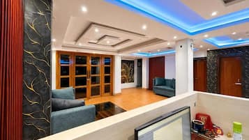 A hotel lobby with a reception desk, seating area, and a large window.