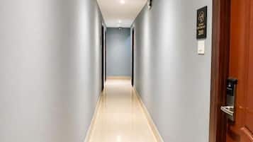 A hallway with a wooden door on the right, a sign above it, and a light-colored floor.