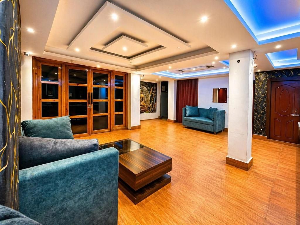 A spacious living area with a wooden floor, a blue sofa, a coffee table, and a large window.