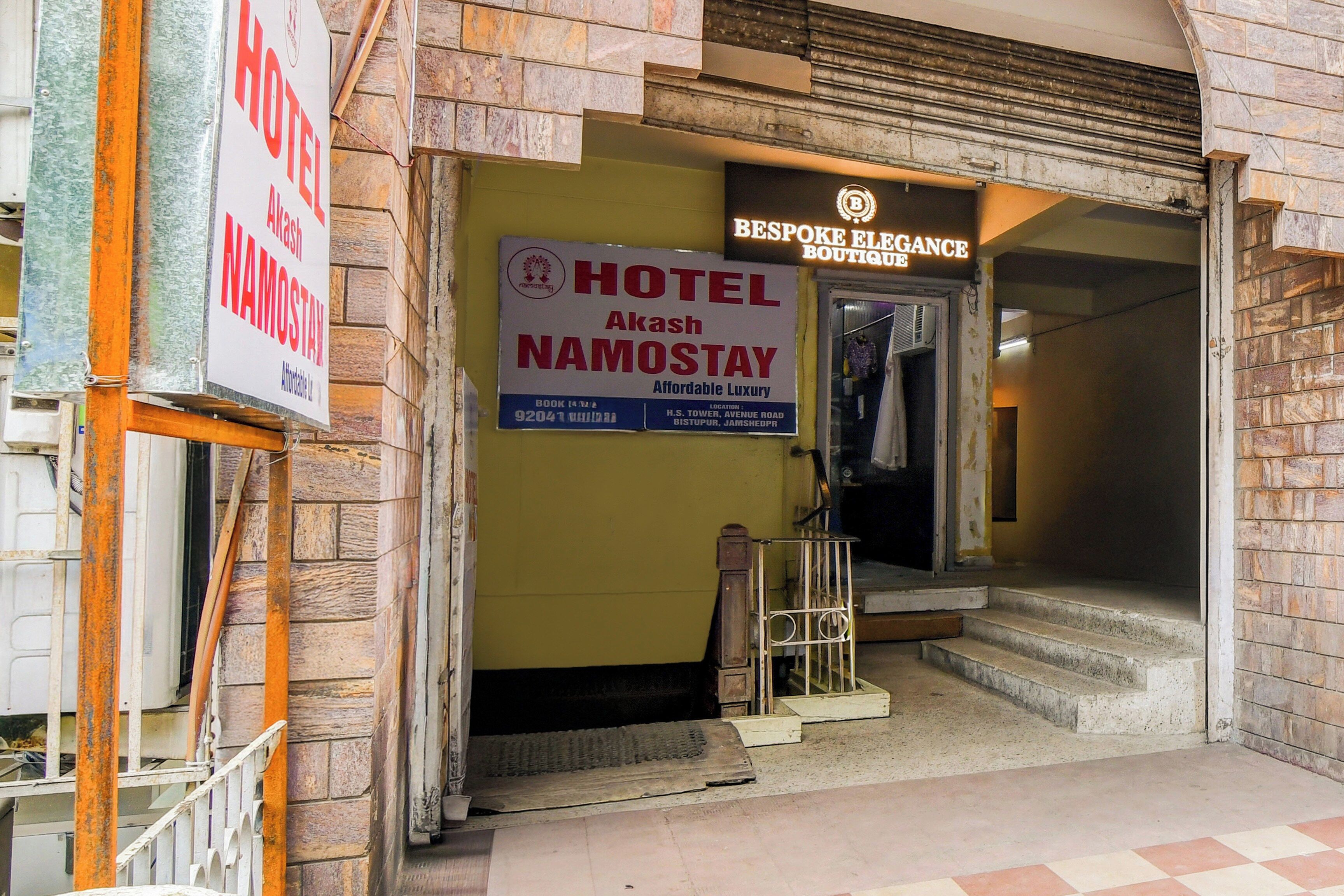 Entrada de un hotel con un letrero que dice 'Hotel Akash Namostay' y una boutique llamada 'Bespoke Elegance Boutique'.