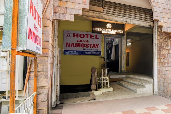 Entrada de hotel com placa indicando 'Hotel Akash Namostay' e uma boutique chamada 'Bespoke Elegance Boutique'.