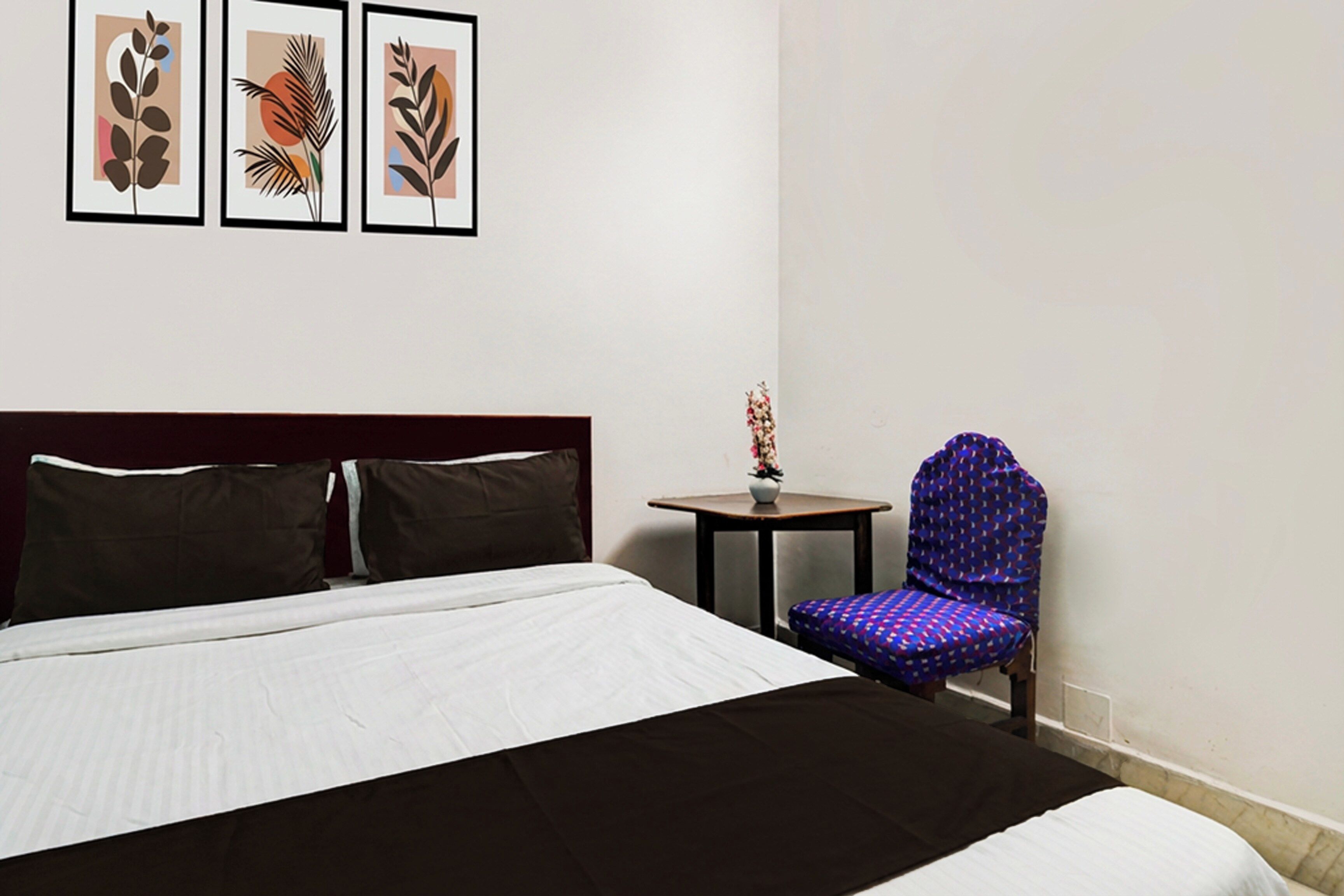 Habitación de hotel con una cama grande, una mesita redonda pequeña, una silla y tres cuadros en la pared.
