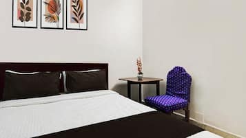 Habitación de hotel con una cama grande, una mesita redonda pequeña, una silla y tres cuadros en la pared.