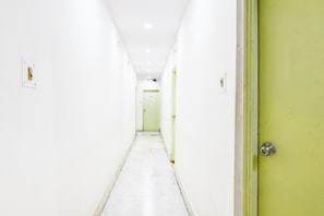 A narrow hallway with white walls and a green door at the end. - Hotel O Akash Namostay (Jamshedpur)