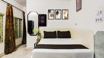Un dormitorio con cama, mesita de noche, espejo, planta en maceta y una obra de arte enmarcada en la pared.