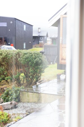 A residential area with modern houses, a paved driveway, and a small garden area with shrubs and a tree. - Hvarvið 9, ST. (Thorshavn)