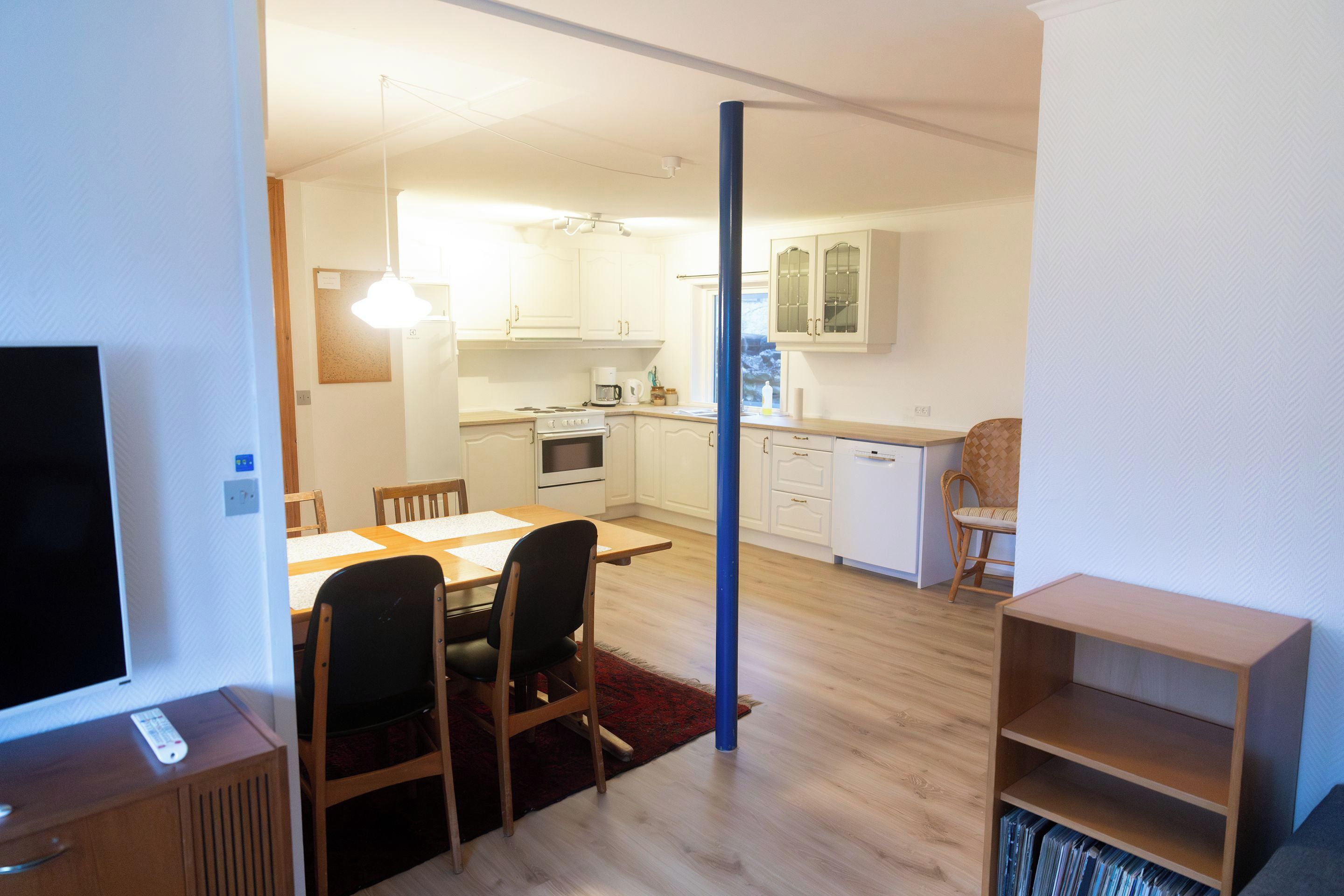 Kompakti oleskelutila, jossa on ruokailualue, pieni keittiö ja televisio.