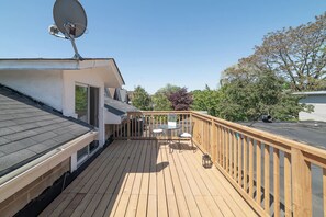 A wooden deck with a satellite dish, a sliding glass door, and a small table with chairs. - Queen Street East Loft | Massive Private Terrace | Parking Available (Toronto)