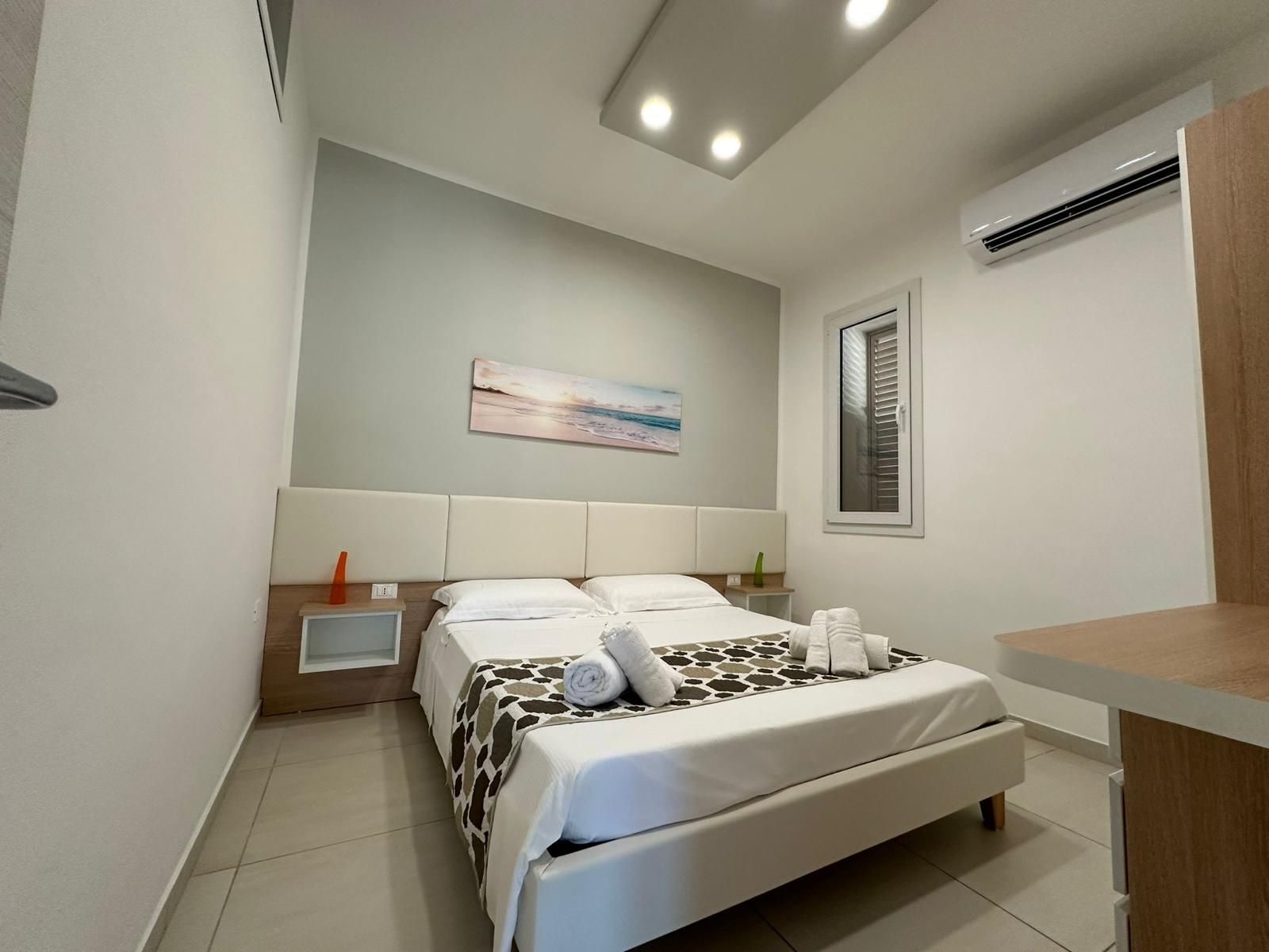 A modern bedroom with a bed, bedside table, and a painting on the wall.