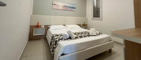 A modern bedroom with a bed, bedside table, and a painting on the wall.