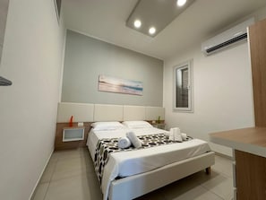 A modern bedroom with a bed, bedside table, and a painting on the wall. - New Listing (Balestrate)