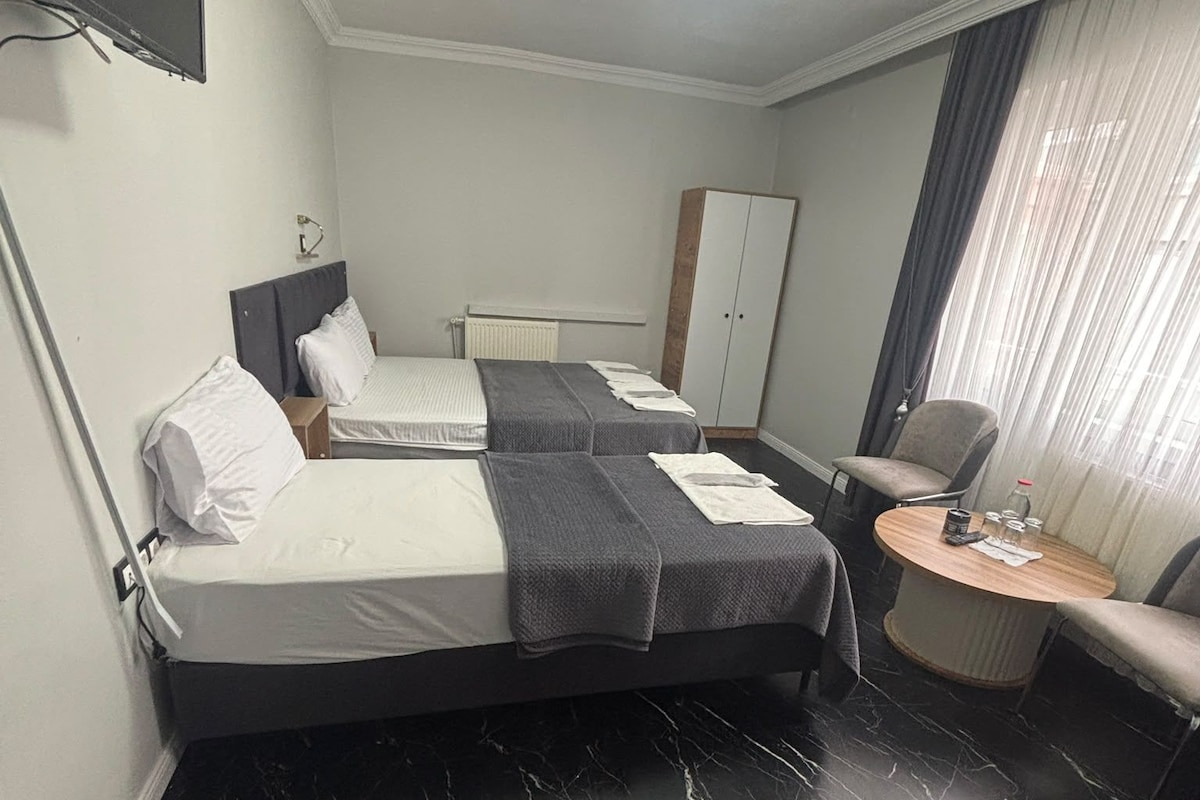 A hotel room with two beds, a desk, a chair, a wardrobe, and a television.