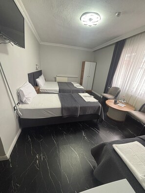 A hotel room with two beds, a desk, a chair, a wardrobe, and a television. - Şelale Apart Otel (Afyonkarahisar)