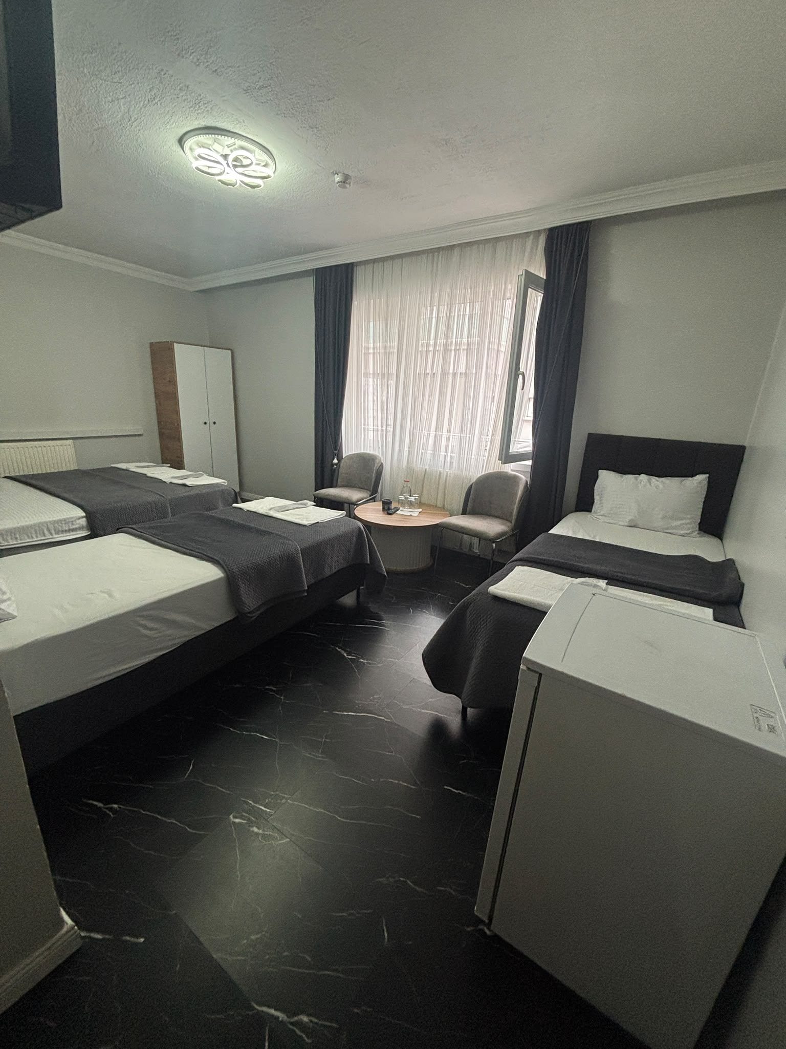 A hotel room with two beds, a desk, a chair, and a wardrobe.