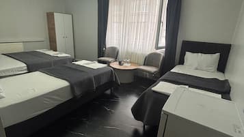 A hotel room with two beds, a desk, a chair, and a wardrobe.