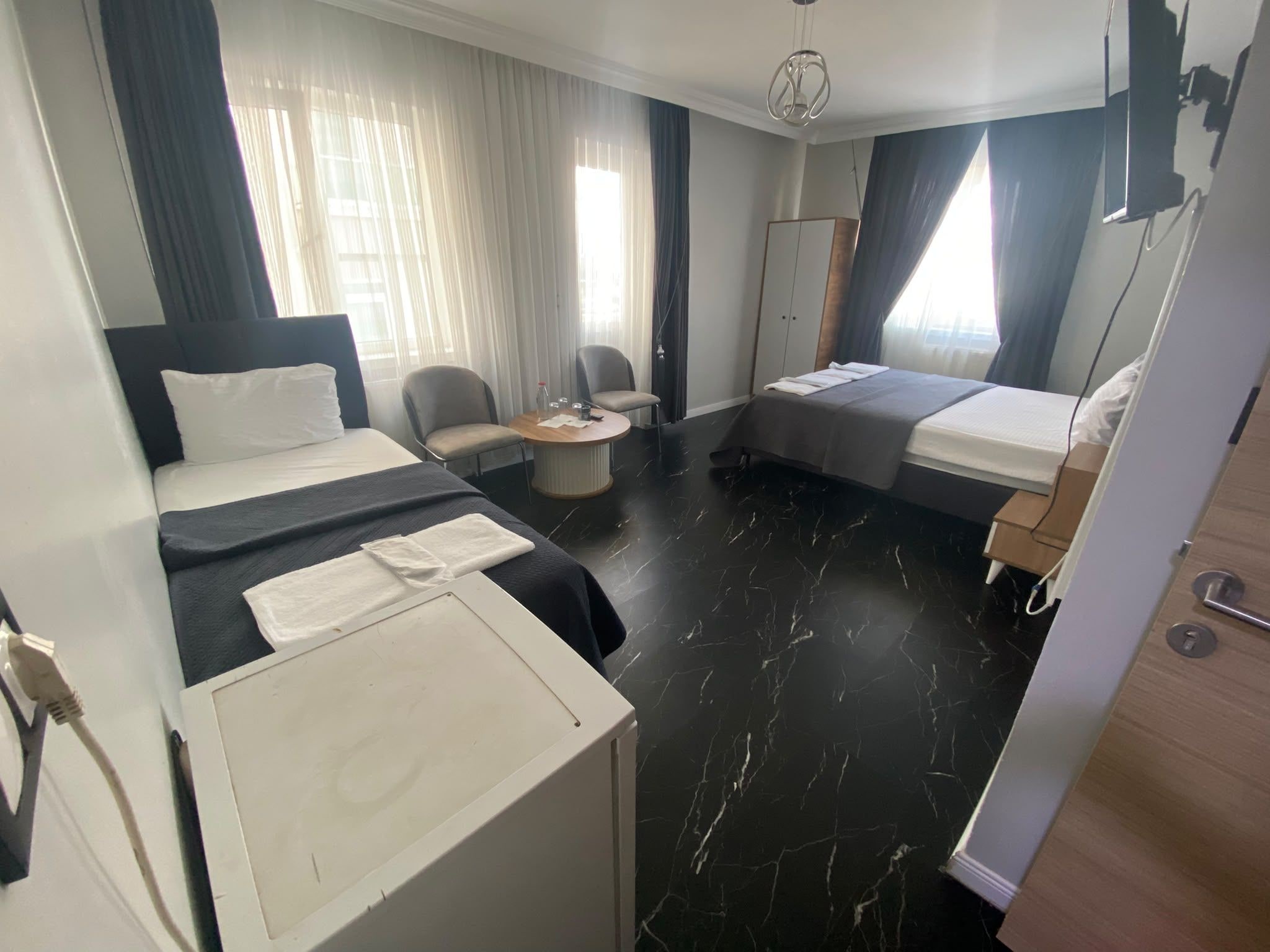 A hotel room with two beds, a desk, a chair, and a wardrobe.