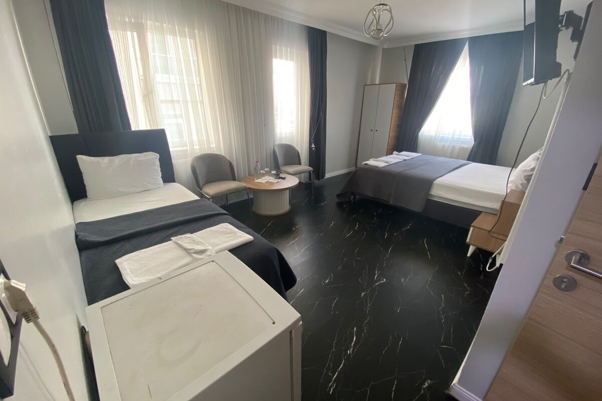 A hotel room with two beds, a desk, a chair, and a wardrobe.