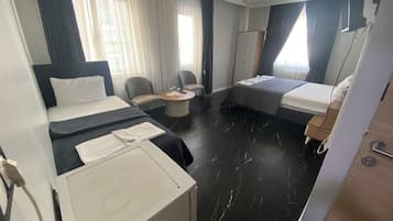 A hotel room with two beds, a desk, a chair, and a wardrobe.