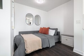 A bedroom with a bed, bedside tables, and two wall-mounted mirrors. - Lakefront Oasis Modern 1BR w Den (Toronto)